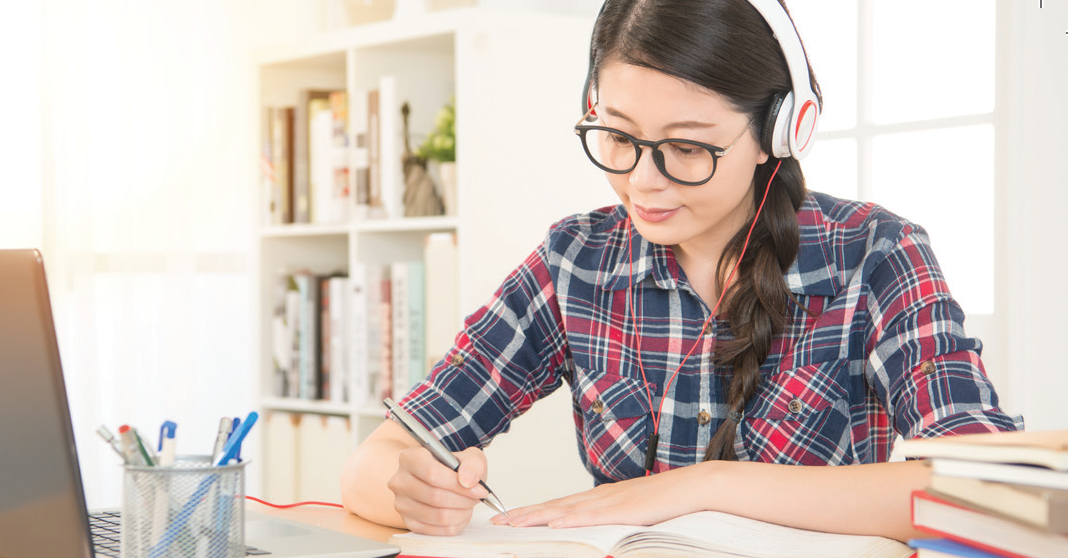 female student studying at home with headphones on